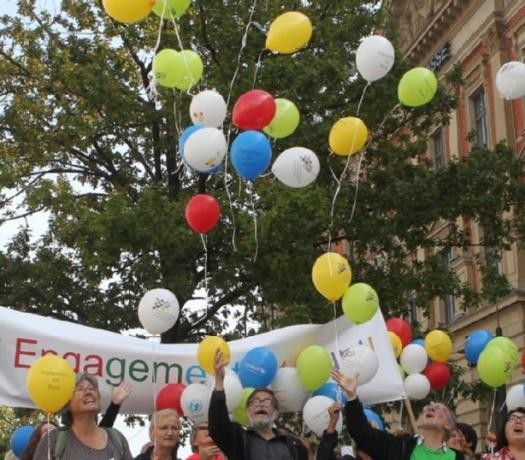 Eine Menschenmenge lässt Luftballons aufsteigen.
