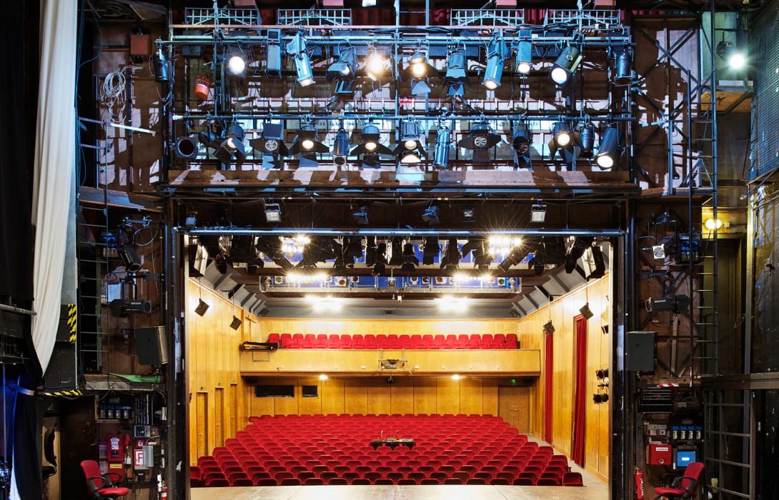 Blick von hinter den Kulissen der Bühne auf den Zuschauerraum des Theaters mit den roten Sitzen