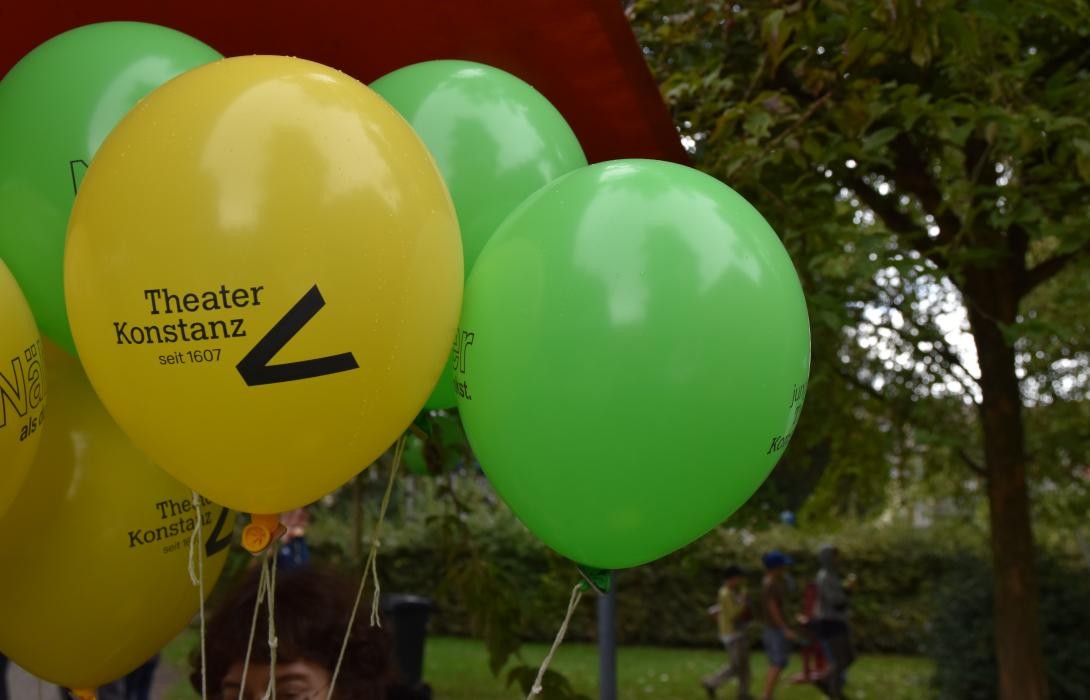 Gelbe und grüne Luftballons an Schnüren mit dem Logo des Theater Konstanz