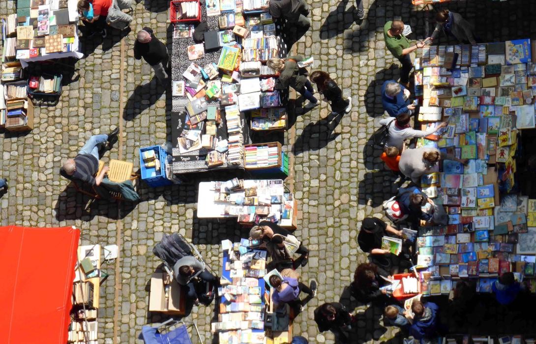 Blick von oben auf Menschen und Tische mit Büchern