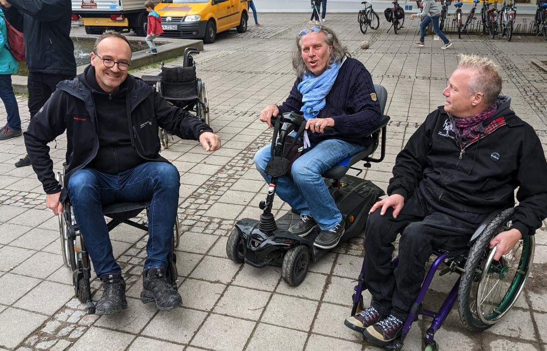 Drei Männer sitzen in Rollstühlen