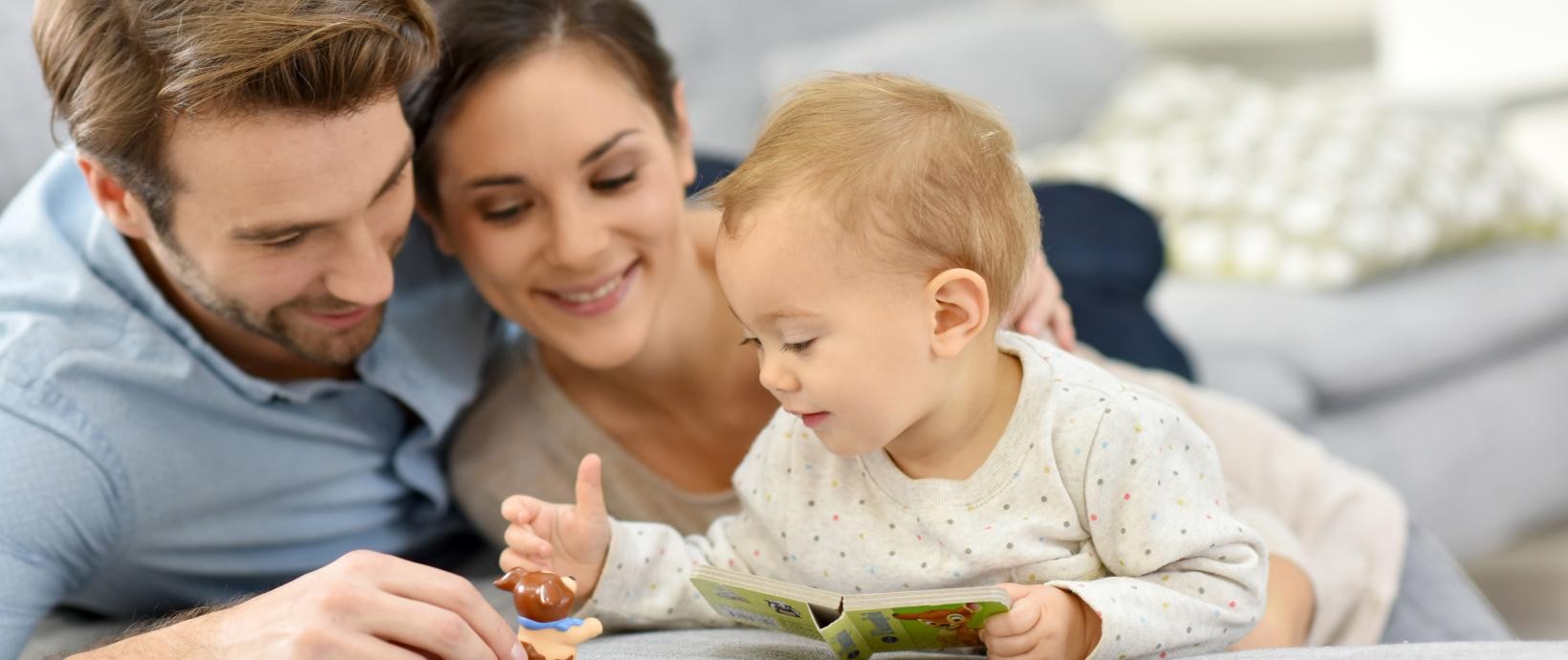 Eltern mit Kleinkind, das ein Bilderbuch in der Hand hält