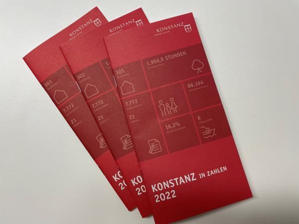 Drei rote Broschüren liegen fächerartig übereinander. Titel: Konstanz in Zahlen 2022.