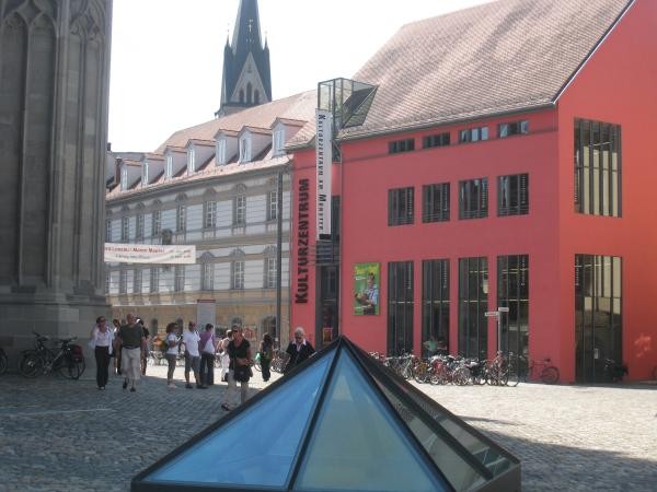 Blick über den Münsterplatz mit Glaspyramide und roter Fassade des Kulturzentrums im Hintergrund