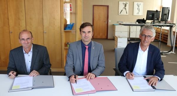 Drei Männer unterzeichnen einen Vertrag