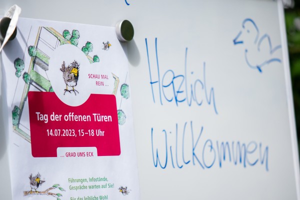 Auf einem Whiteboard steht neben dem Flyer vom Tag der offenen Tür: "Herzlich Willkommen"