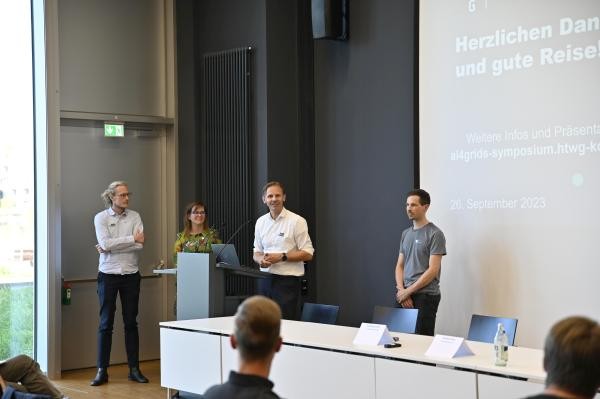 Vier Personen stehen während eines Vortrags vor einer Projektionsfläche