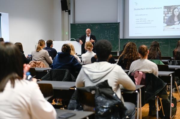 Blick von hinten auf eine Reihe Studierende in einem Hörsaal