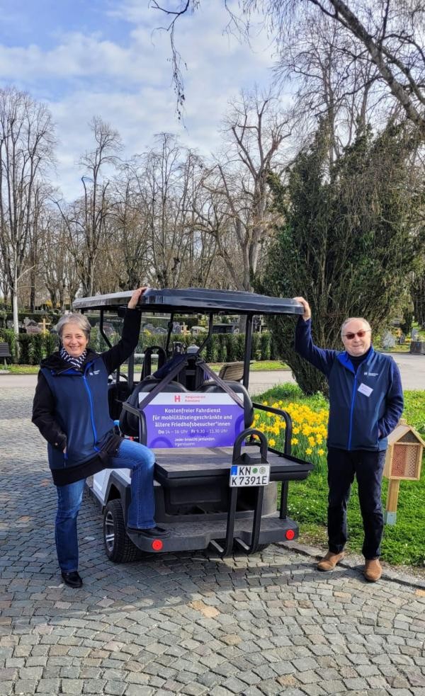 Eine Frau und ein Mann stehen links und rechts neben einem Caddy