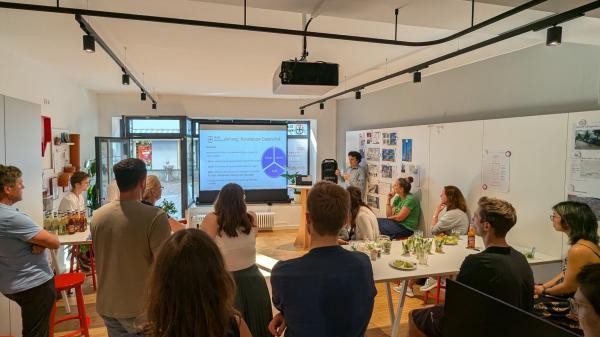 mehrere Personen sitzen in einem Raum und hören einem Vortrag zu