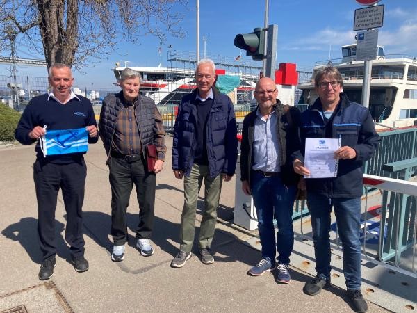 Vertreter der Internationalen Wassersportgemeinschaft überreichen die Urkunde an Fähre-Mitarbeiter im Fährehafen Konstanz-Staad.