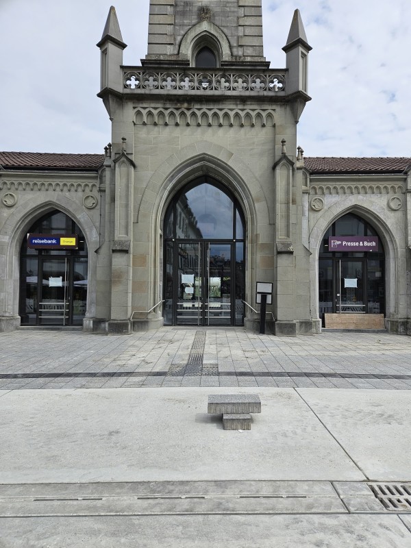 Der Eingang des historischen Konstanzer Bahnhofsgebäudes ist mit grauen, flachen Pflastersteinen barrierefrei gestaltet.