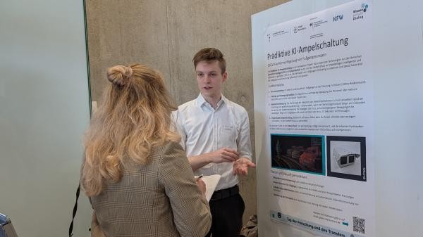 mehrere Personen stehen neben Plakat zur Prädiktiven KI-Ampelschaltung