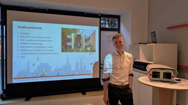 eine Person steht vor eine Präsentation mit Inhaltsverzeichnis und Foto einer Fußgänger-ampel.