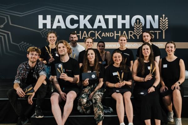 Gruppenbild mit zwölf Personen in dunklen T-Shirts. Im Hintergrund „Hackathon hack and Harvest“.