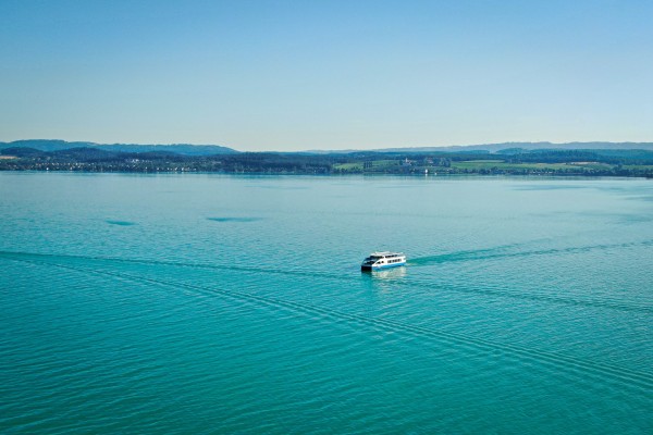 Ein Schiff fährt über den blauen Bodensee, Aufnahme von oben.