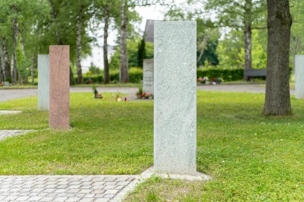 Ein länglicher Block aus grau marmoriertem Stein steht auf einem Rasen.