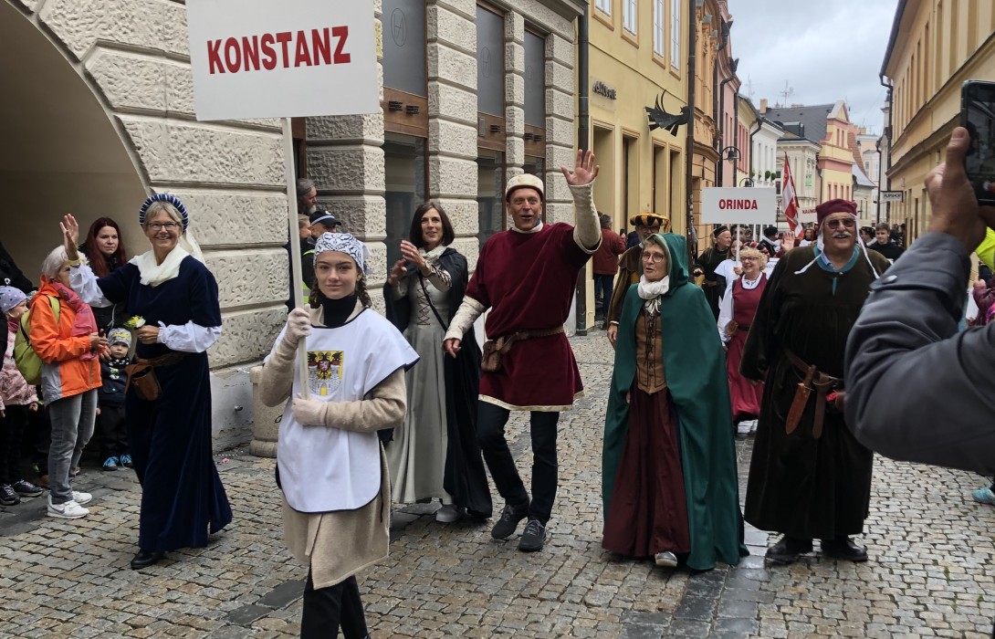 Personen laufen in mittelalterlichen Kostümen in einem Umzug, vorne trägt eine Person ein Schild mit "Konstanz".