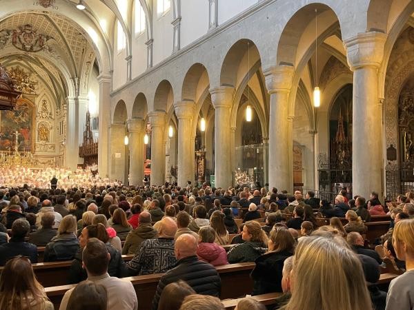 Blick von hinen über Kirchenbänke gefüllt mit Zuschauern hin in den Altarraum, wo ein Kinderchor steht.