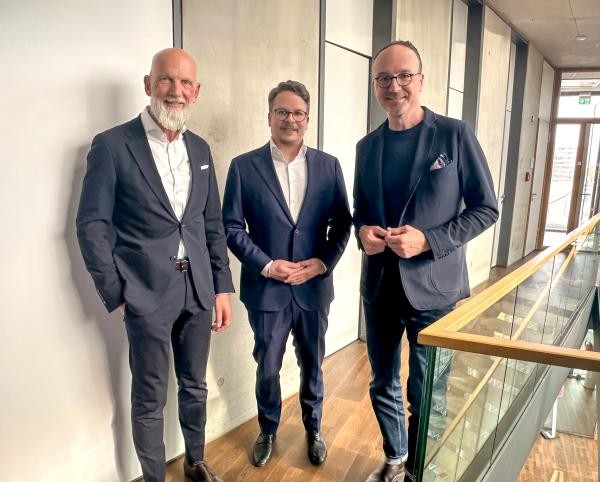 Drei Männer mit Anzügen stehen nebeneinander