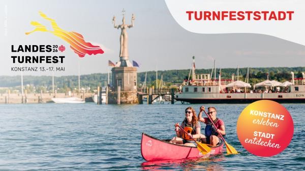 Im Vordergrund sitzen zwei Personen in einem roten Kanu mit zwei Paddeln auf dem Bodensee. Im Hintergrund ist die Statue der Imperia zu sehen und ein Schiff.