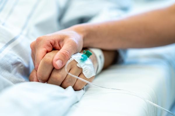 Symbolbild: sich haltende Hände im Krankenbett