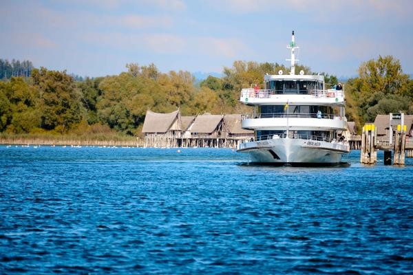 Ein weißes Schiff mit Pfahlbauten im Hintergrund