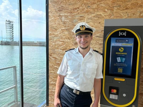 Hafenmeister in Uniform neben einem Fahrscheinautomat