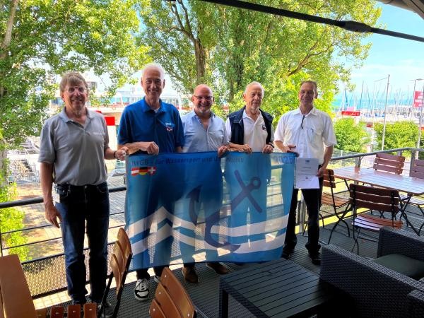 Fünf Männer halten eine blaue Flagge in der Hand.