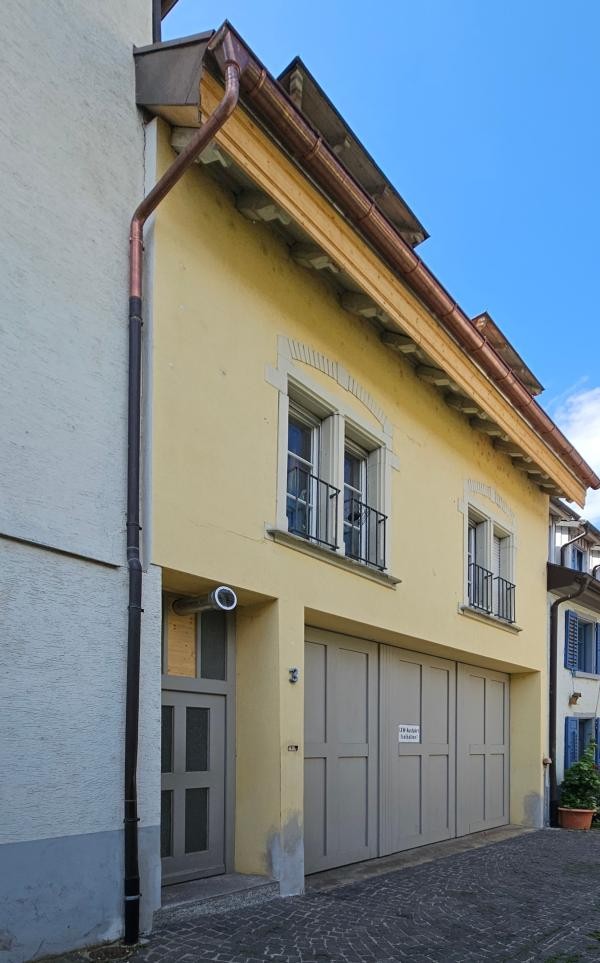 Hellgelbe Hausfassade mit grauen Garagentoren