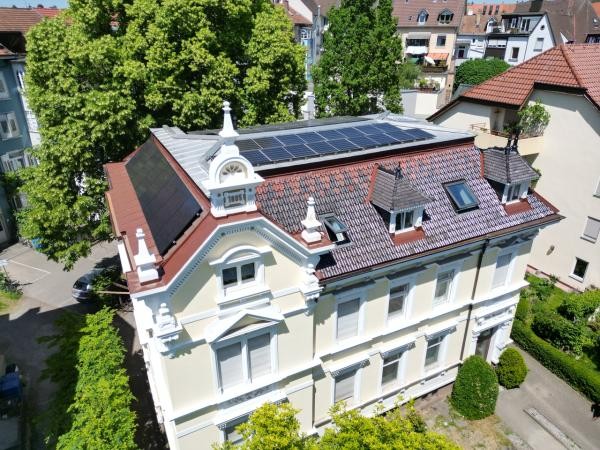 Blick von oben auf eine hellgelbe Gründerzeitvilla mit Photovoltaikanlage auf dem Dach
