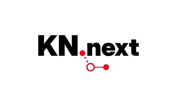 Logo „KN.next" in schwarzer Schrift mit einem roten Punkt statt eines Punktes zwischen KN und next, darunter ein grafisches Element aus zwei kleinen Punkten und einem verbundenen Kreis-Symbol.