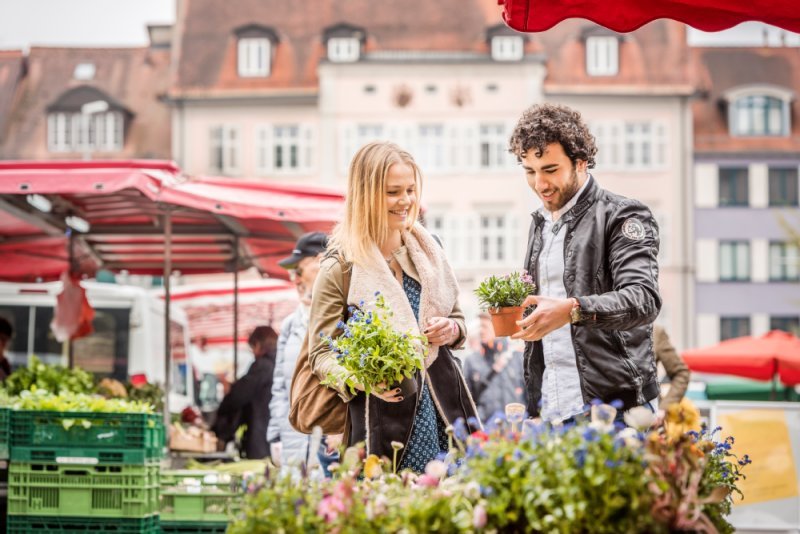Eine Frau und ein Mann kaufen Blumen auf dem Wochenmarkt.