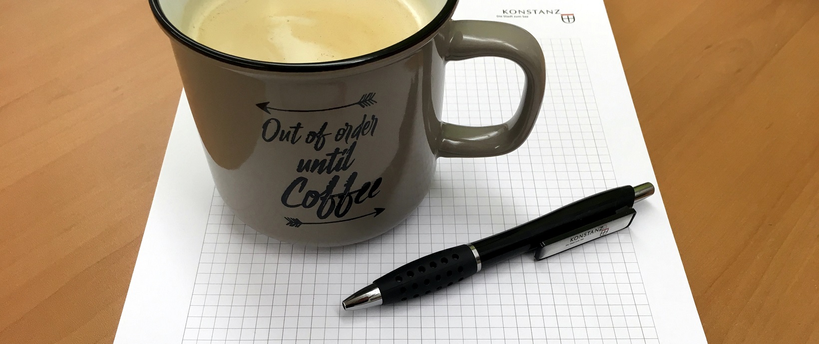 Kaffeetasse und Kugelschreiber auf einem karierten Block