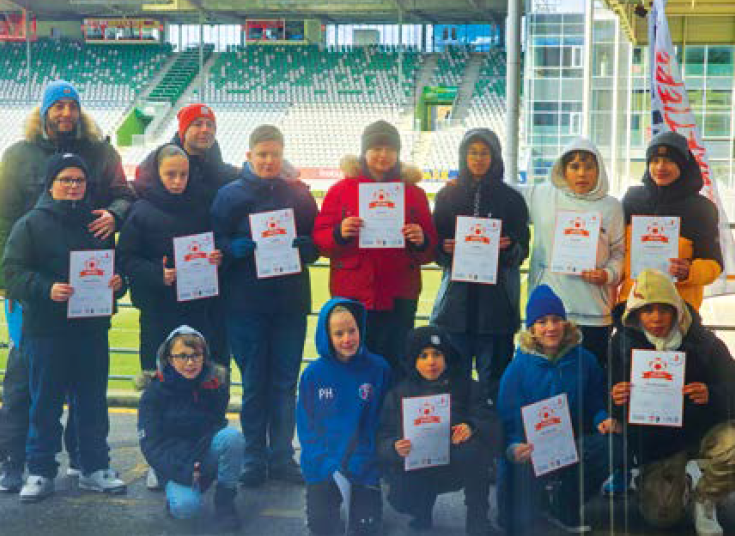 Eine Gruppe von Jungen auf einem Fußballplatz hält Zertifikate in den Händen