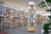 Ein Bücherregal voller Bücher steht inmitten weiterer, größerer Bücherregale im Hintergrund.